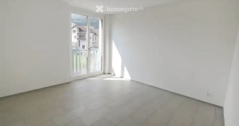 Empty room with white walls, tiled floor, and large sliding glass door leading to a balcony.