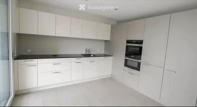 Modern kitchen with white cabinets, black countertops, and built-in appliances including a sink and oven.