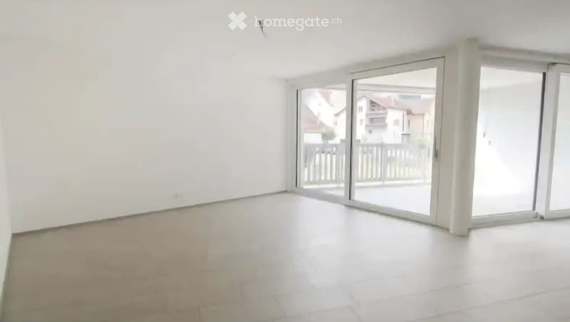 Empty room with white walls, tiled floor, and large sliding glass doors leading to a balcony.