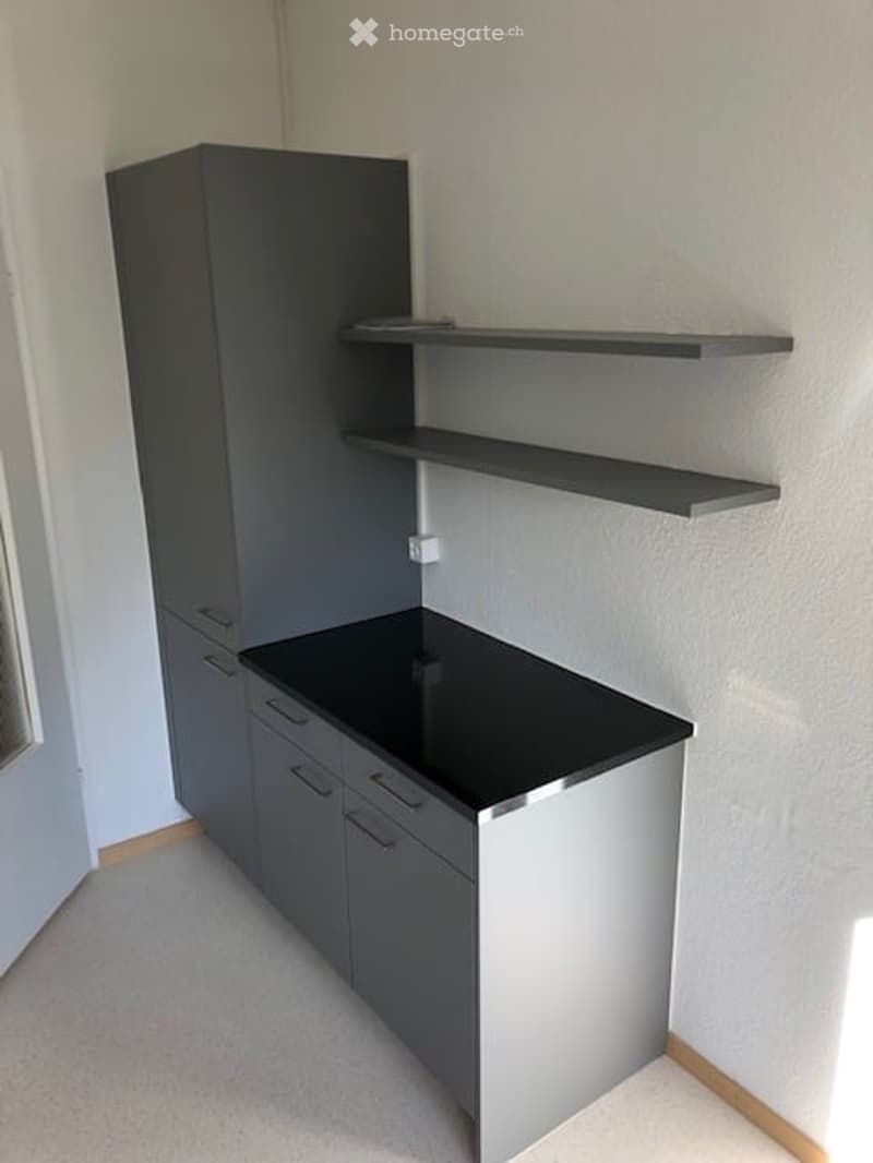 Empty room with grey cabinetry and black countertop, no furniture or items present.