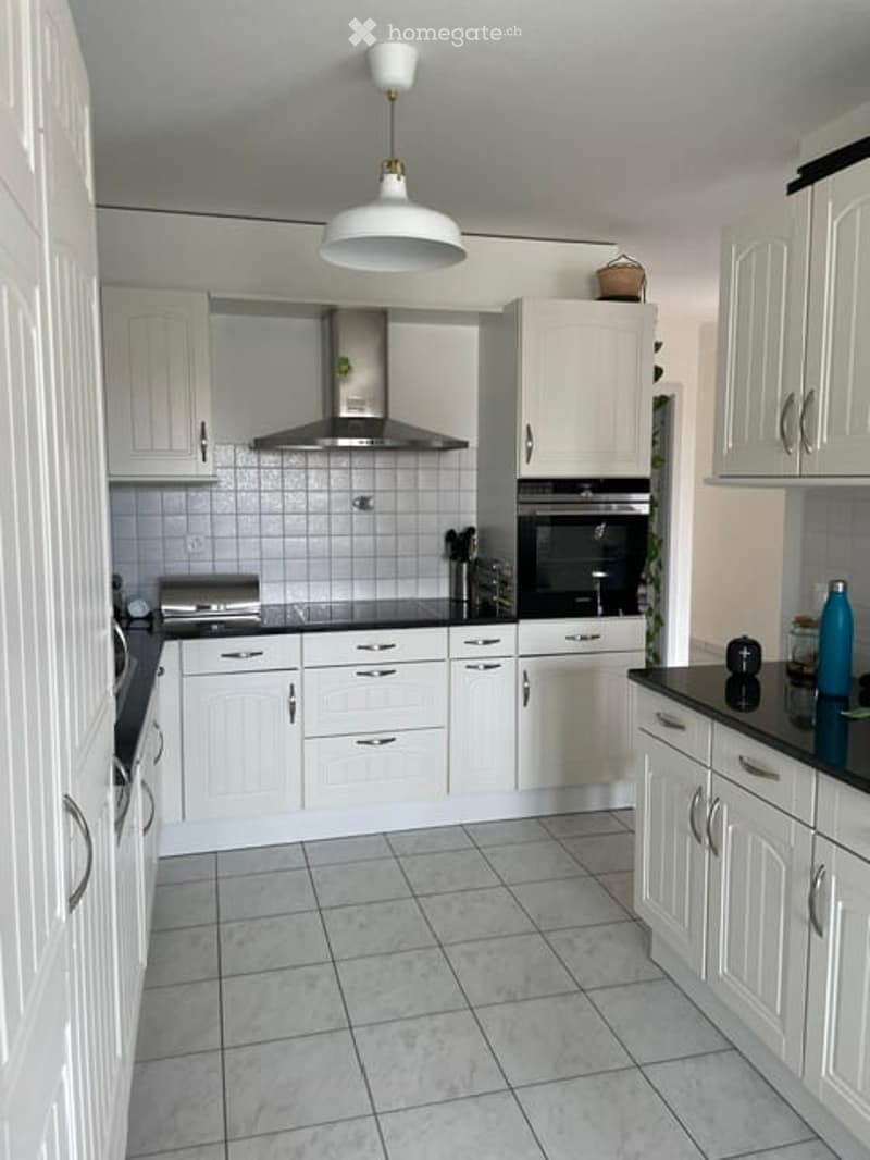 Modern kitchen with white cabinets, stainless steel appliances, and a black countertop.