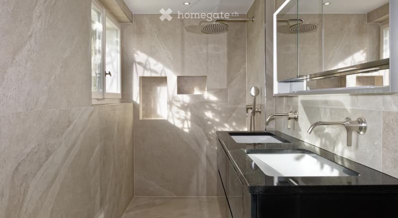Modern bathroom with beige stone tiles, double sink vanity, large mirror, and a walk-in shower with a glass enclosure.