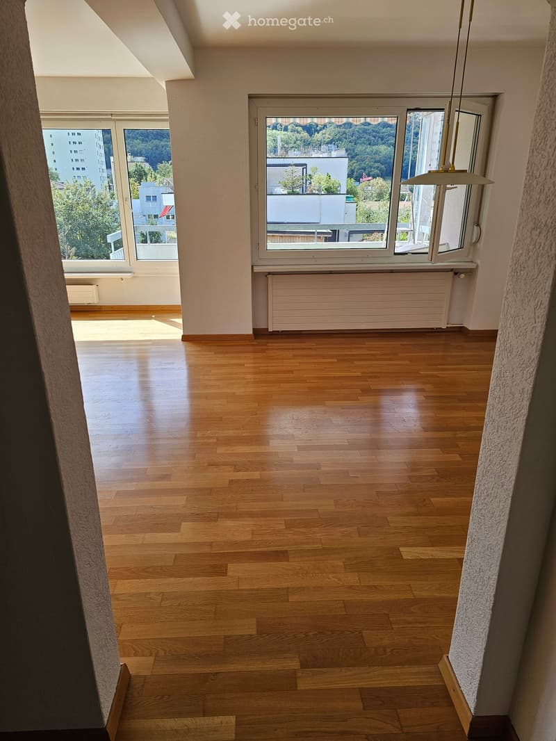 Empty room with wooden flooring, large windows, and radiators. No furniture or equipment present.