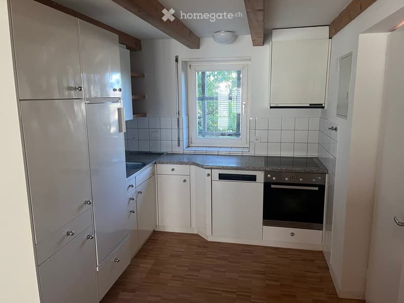 Modern kitchen with white cabinets, stainless steel appliances, granite countertop, and wooden flooring.