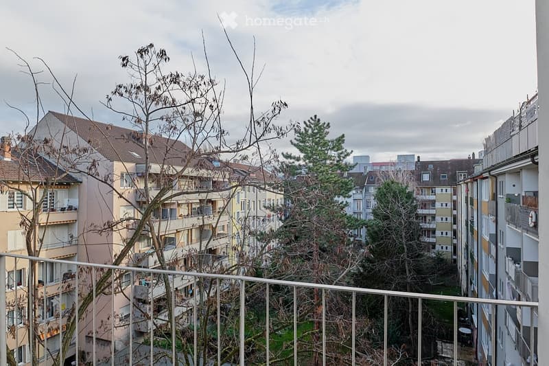 View from a balcony of several apartment buildings, balconies, trees, and a grassy area