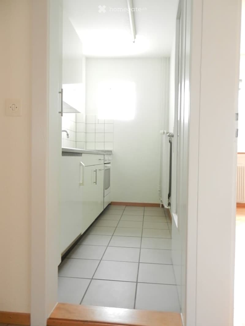 Modern kitchen with white cabinets, tiled floor, and a sink with a faucet.