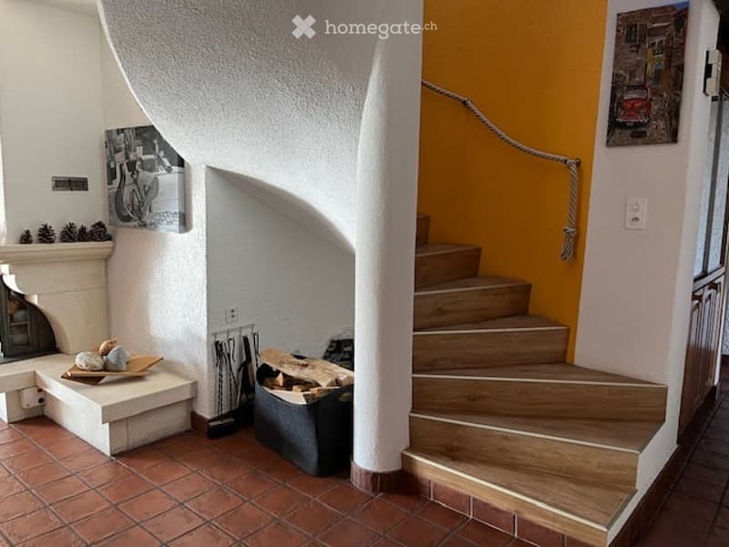 Hallway with a wooden staircase, a fireplace, and a small bench with decorative items on it.
