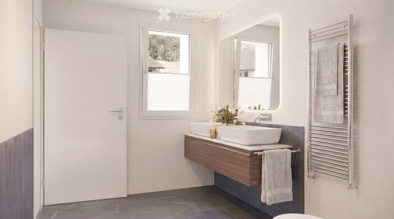 Modern bathroom with two white sinks, a wooden vanity, a large mirror, a towel rack, and a decorative flower arrangement.