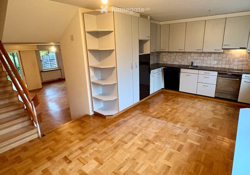 Modern kitchen with white cabinets, wooden flooring, and stainless steel appliances including a sink, oven, and fridge.