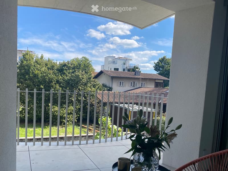 Balcony with tiled floor, white metal railing, and a view of a residential area with trees and houses.