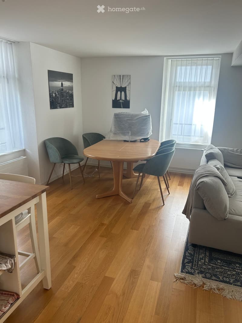 Living room with hardwood floors, a sofa, a dining table with chairs, and artwork on the walls.