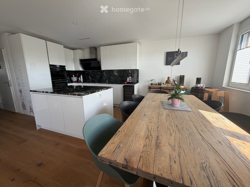 Modern kitchen and dining area with white cabinets, a wooden dining table, and various appliances.