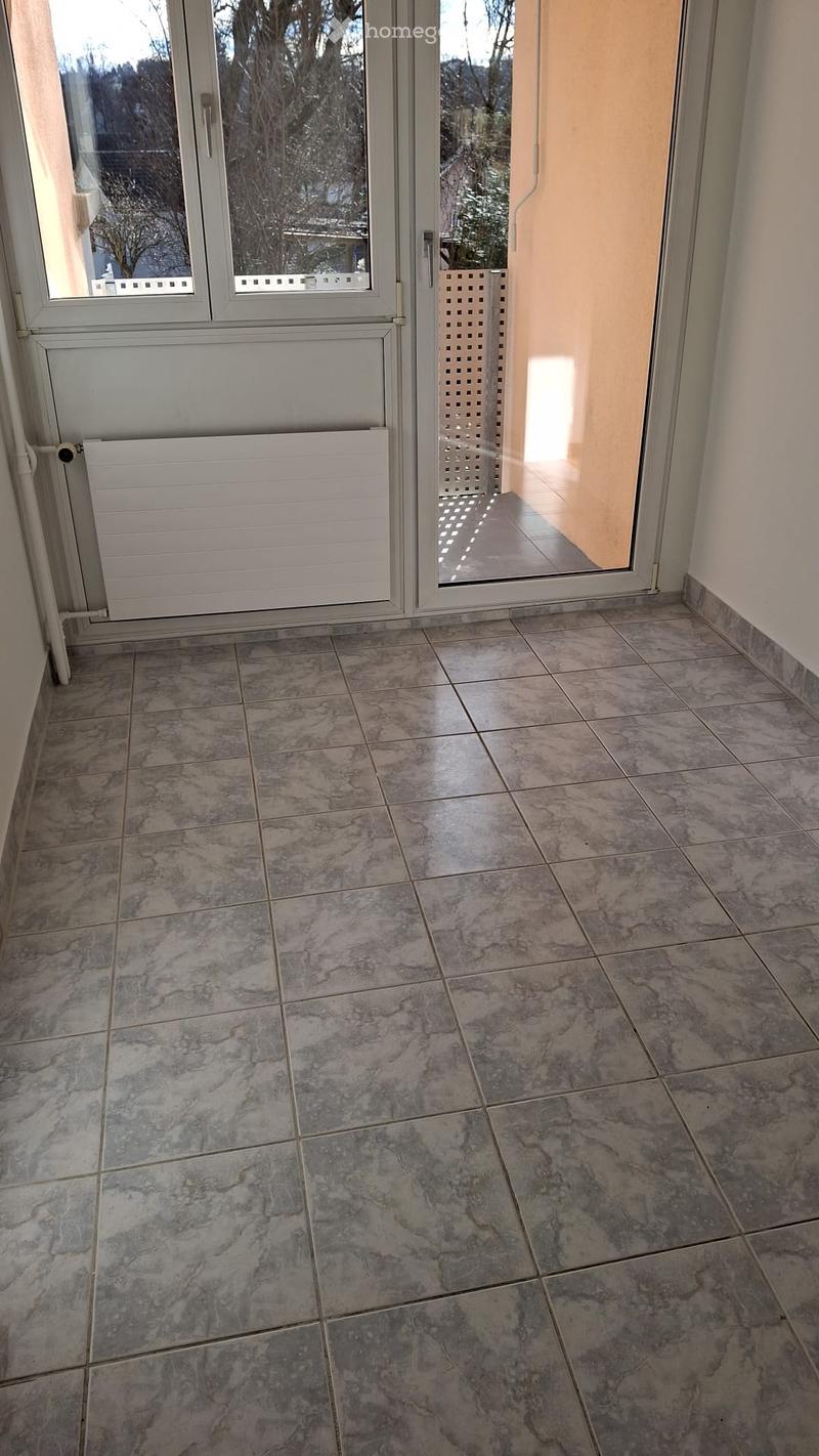 Empty room with tiled floor, large glass sliding door leading outside, radiator, and a decorative screen.