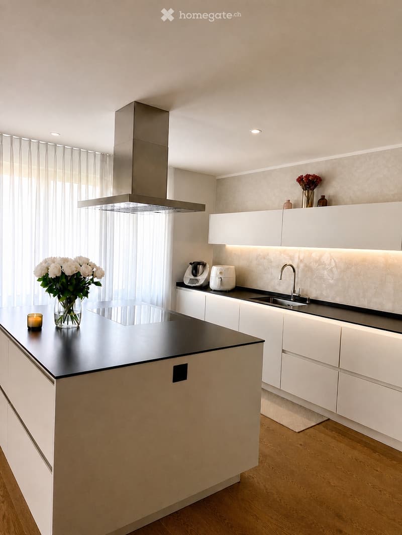 Modern kitchen with white cabinets, black countertop, island, sink, and appliances.