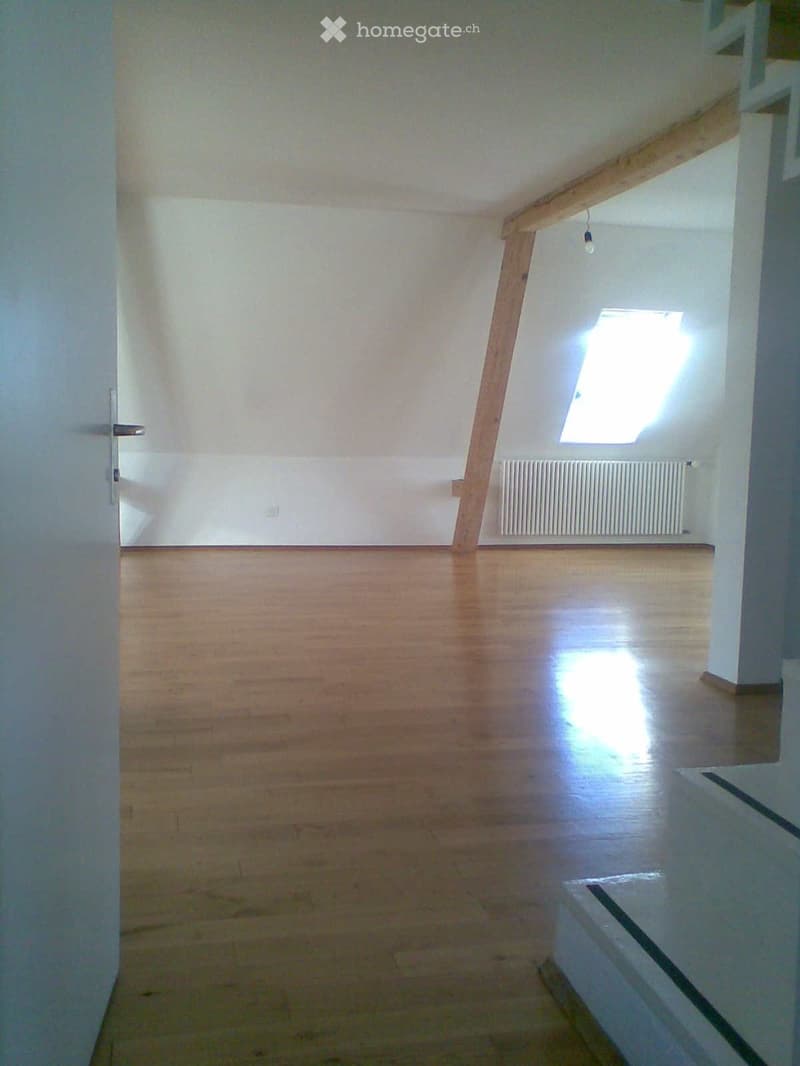 Empty room with wooden flooring, white walls, and a skylight window letting in natural light. No furniture or equipment is present.