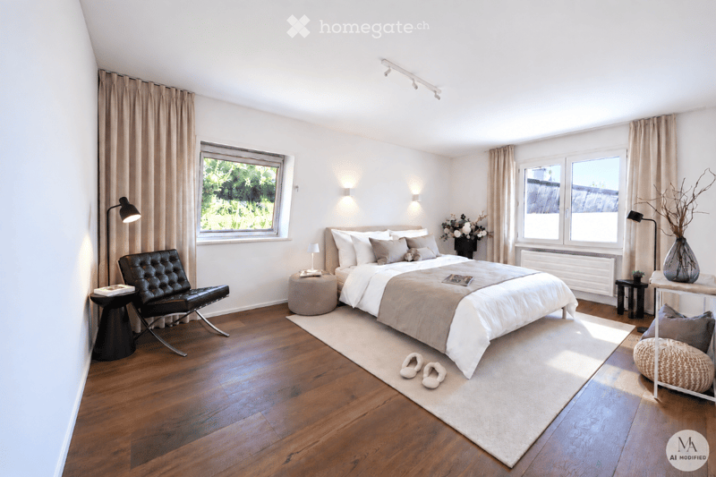 Modern bedroom with wooden flooring, large bed with white bedding, nightstand, black leather chair, side table, and decorative vase.