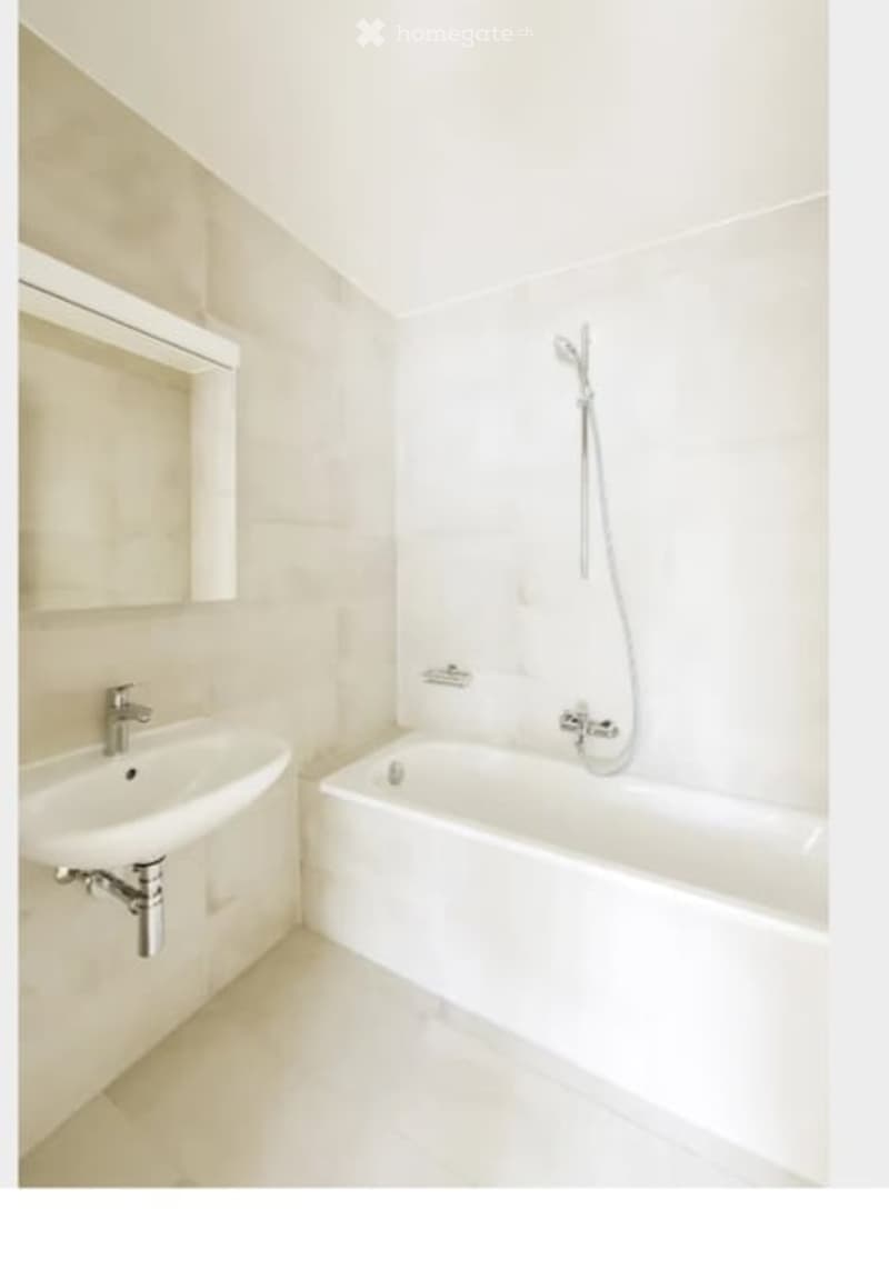 Modern bathroom with a white sink, bathtub, and mirror. The space features clean lines and a neutral color palette.