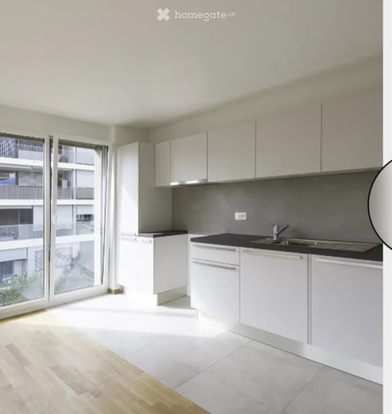 Modern kitchen with white cabinets, black countertops, and a large window offering a view of the balcony.
