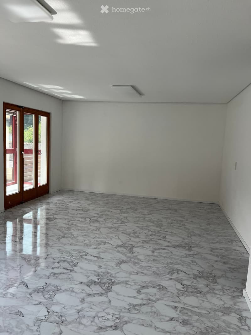 Empty room with marble flooring, white walls, and a large sliding glass door leading outside.