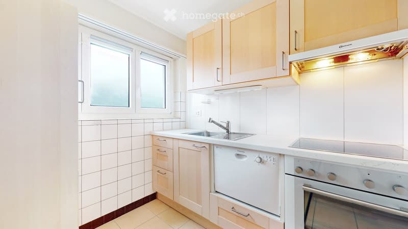 Modern kitchen with white cabinets, a sink, a dishwasher, and an oven. The space features tiled walls and a window providing natural light.