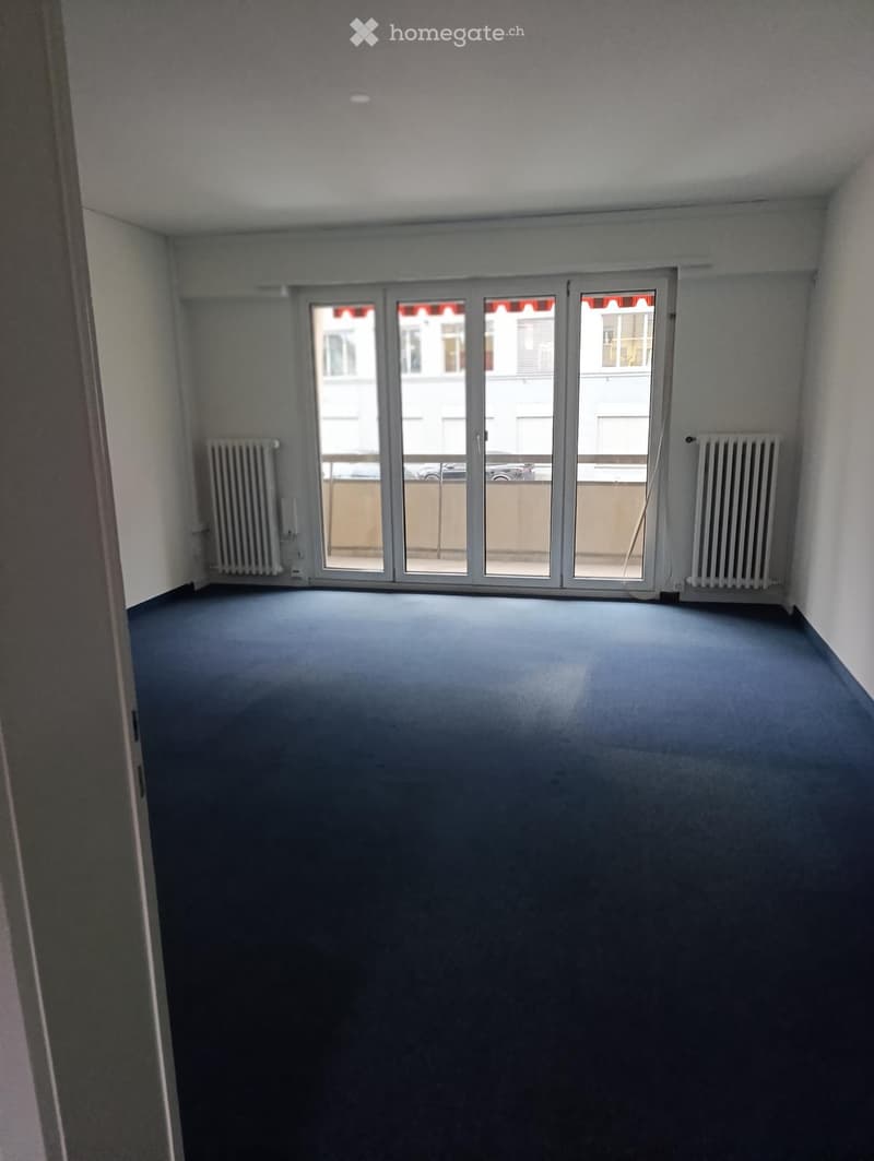 Empty room with blue carpet, white walls, and large sliding glass doors leading to a balcony area.