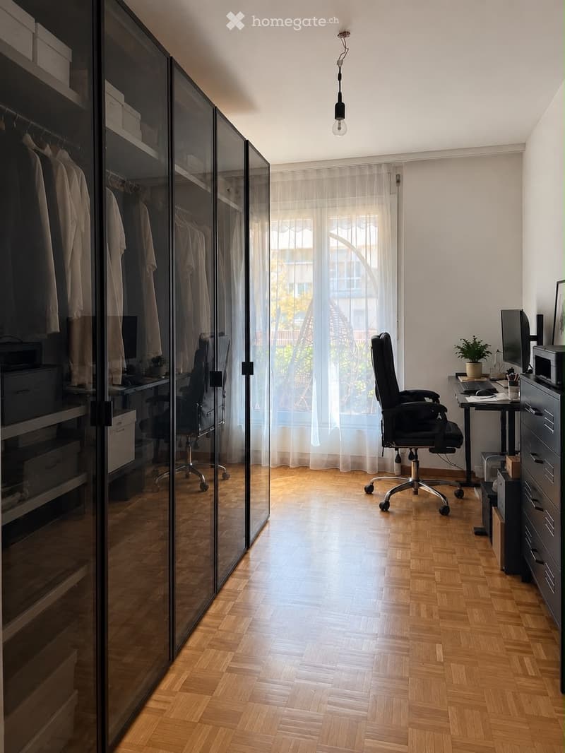 Modern office space with wooden flooring, large window with sheer curtains, glass wardrobe, desk with chair, computer screen, and small plant.