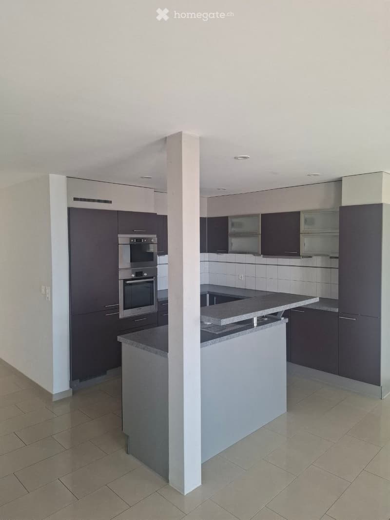 Modern kitchen with dark cabinets, stainless steel oven, and a central island with a granite countertop.