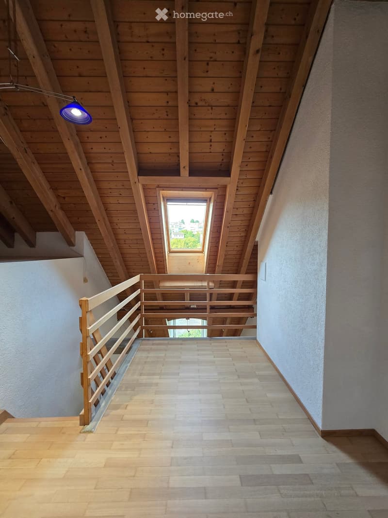 Wooden staircase with a wooden railing, leading to a skylight in the ceiling, with wooden walls and flooring.