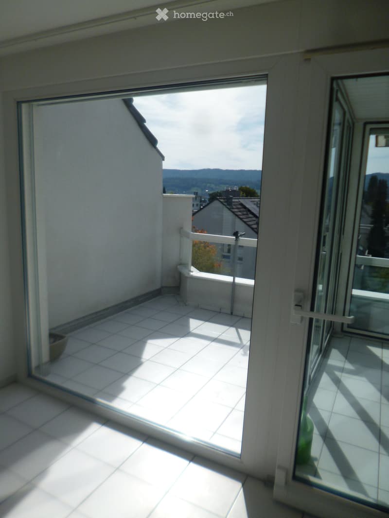 Balcony with tiled floor, glass sliding doors, and a view of the surrounding landscape.