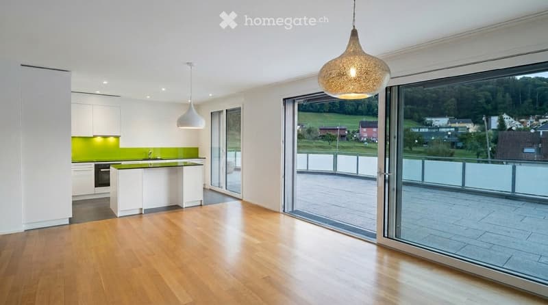 Modern kitchen with white cabinets, green backsplash, wooden flooring, and large windows offering a scenic view.