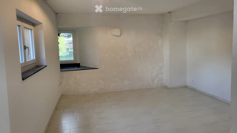 Empty room with tiled floor, white walls, and two windows with black sills.
