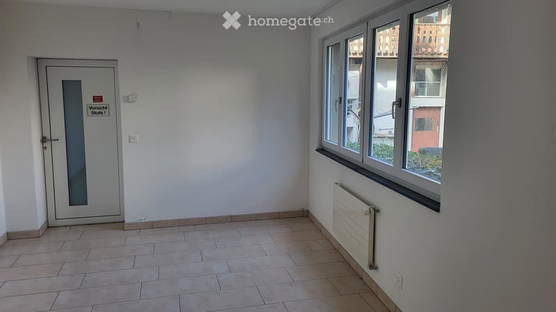 Empty room with tiled floor, white walls, a door, and a window with a radiator below it.