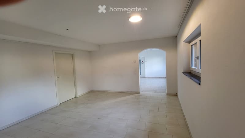 Empty hallway with tiled floor, white walls, a single door, and a window with a small shelf. No furniture or equipment present.