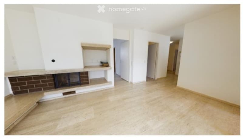 Empty living room with white walls, tiled floor, and a built-in brick fireplace with wooden shelf above it.