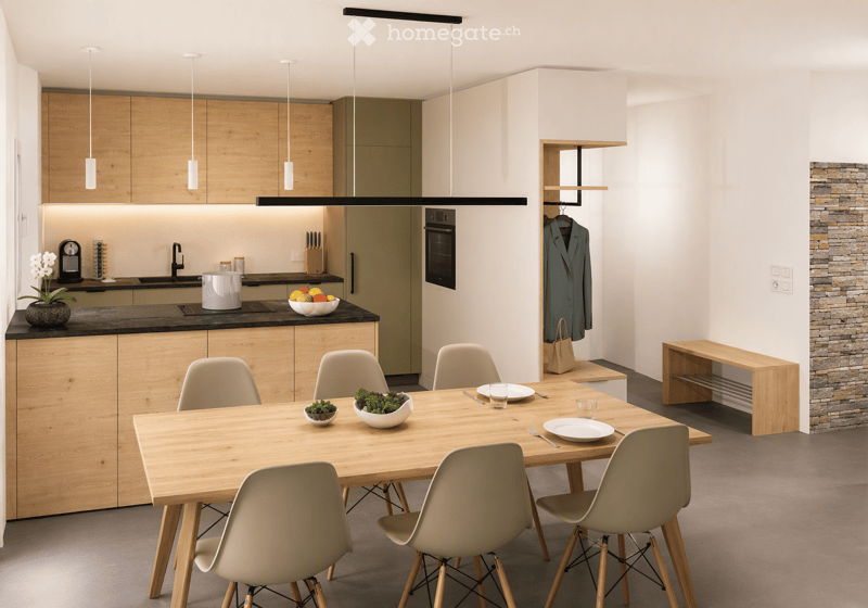 Modern kitchen and dining area with wooden cabinets, a central island, and a dining table surrounded by chairs. The space features pendant lights, a stone accent wall, and various kitchen appliances.