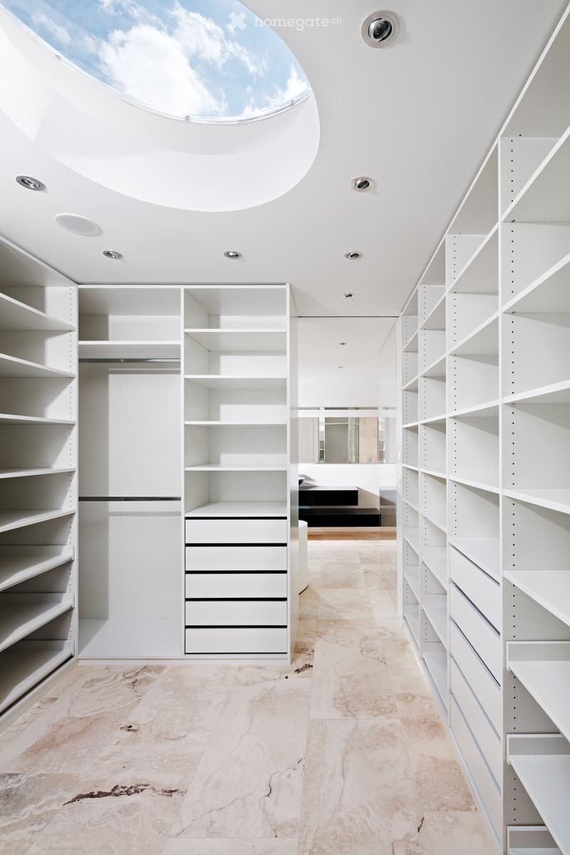 walk-in closet with white shelves, drawers, marble floor, skylight