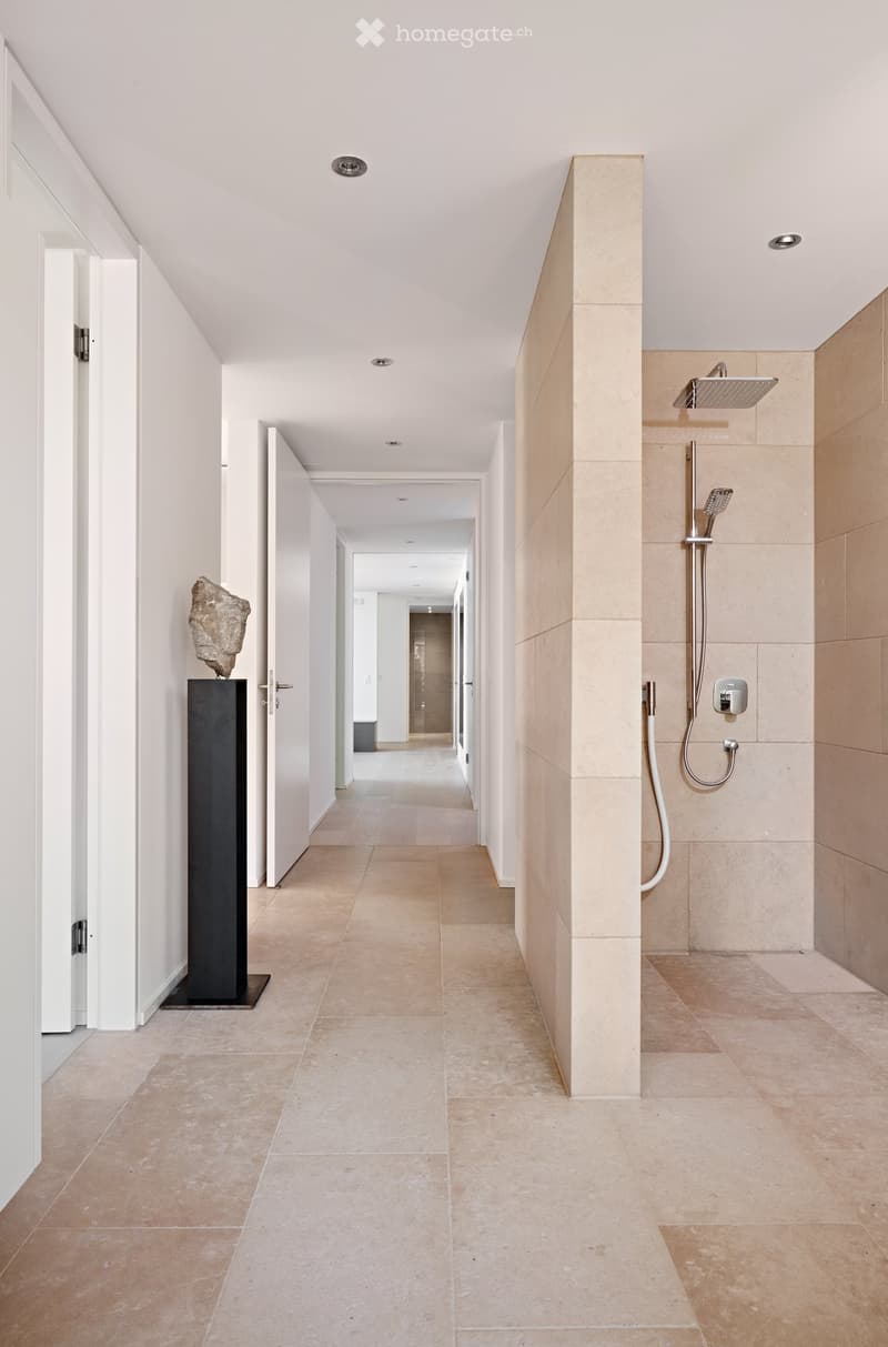 empty hallway with shower, statue, beige flooring, white walls