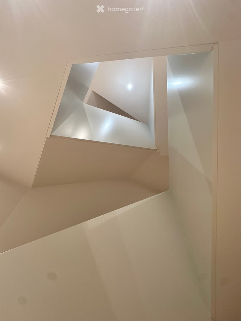 Modern interior view of a corridor with geometric, angular ceiling design and soft lighting.