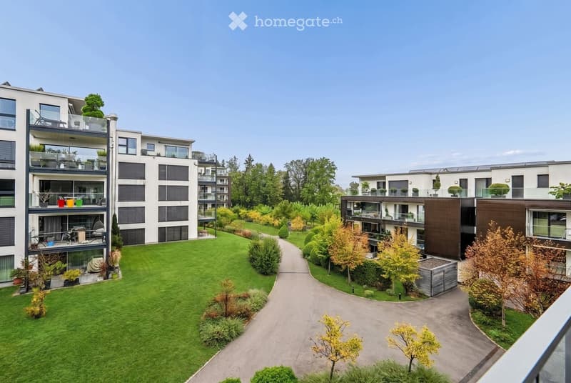 Modern residential complex with multiple apartment buildings, balconies, and landscaped gardens.