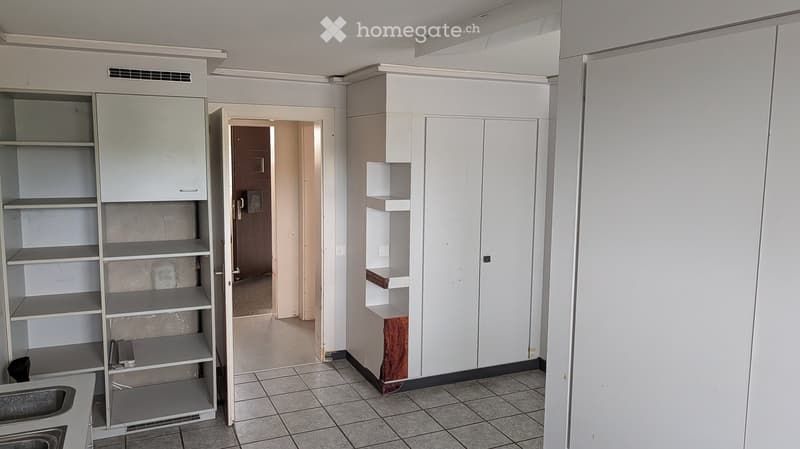 Empty room with white cabinets, tiled floor, and an open doorway leading to another space.