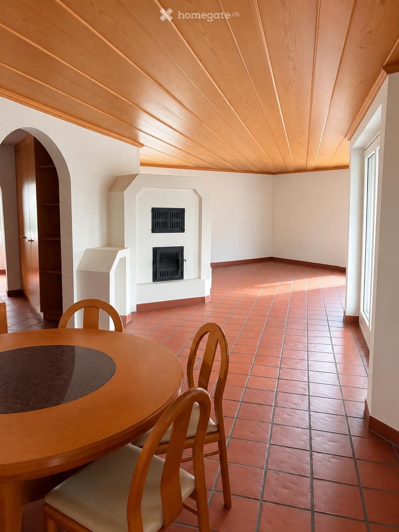 Dining area with a wooden dining table, chairs, and a fireplace in the background.