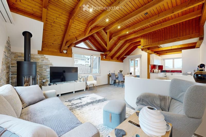 Open-plan living and dining area with exposed wooden beams, a modern fireplace, a large TV, and comfortable seating including a sofa, armchair, and ottoman.