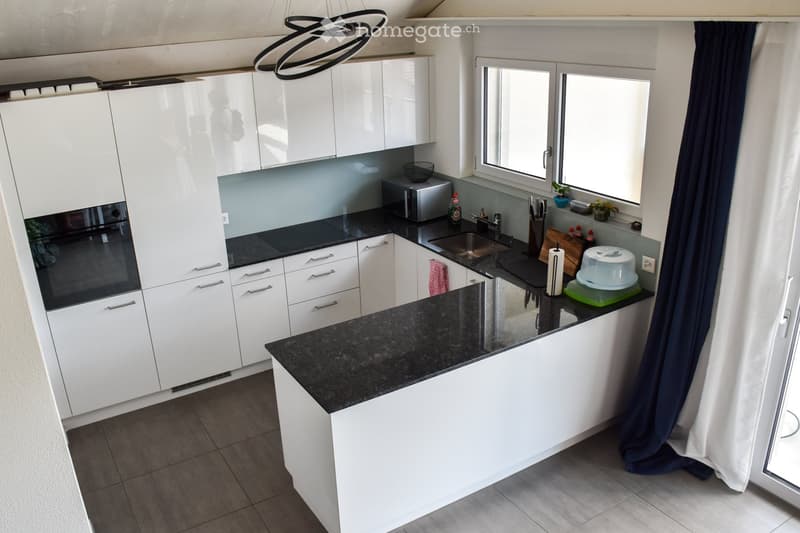 Modern kitchen with white cabinets, black granite countertops, stainless steel appliances, and a central island.