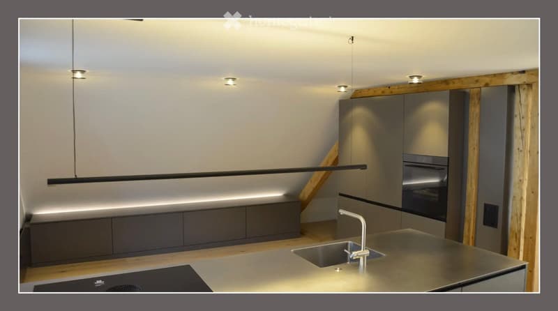 Modern kitchen with stainless steel sink, faucet, built-in oven, and sleek cabinetry.