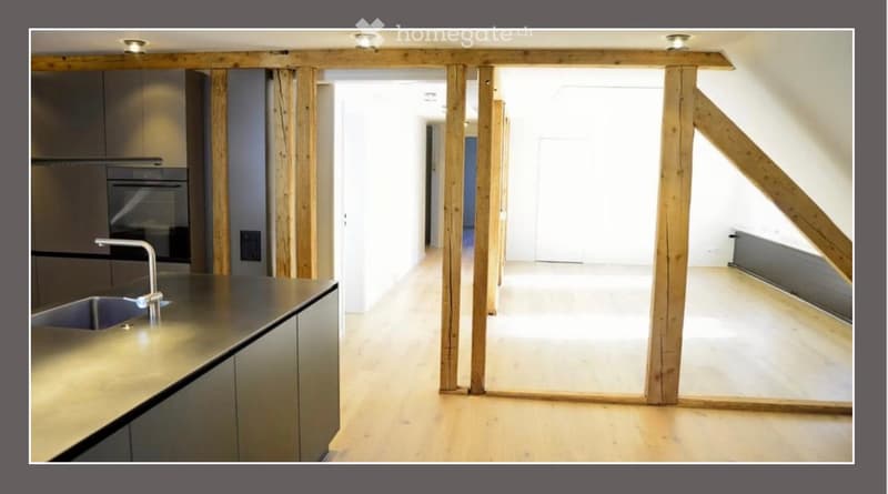 Modern kitchen with stainless steel sink, faucet, oven, and cabinets, connected to an open wooden-framed space.