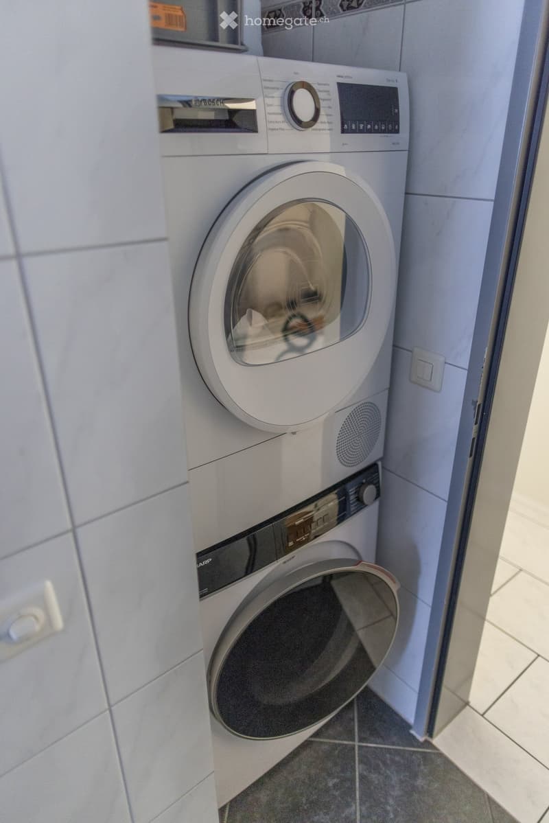 A modern bathroom with a Bosch washing machine and a Sharp dishwasher installed side by side.