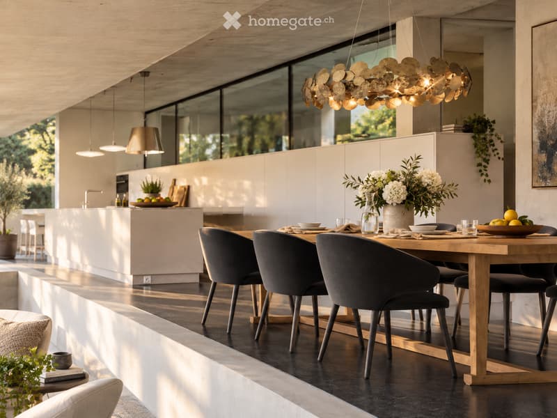 Modern dining area with a wooden dining table, black chairs, pendant light, and a kitchen island in the background.