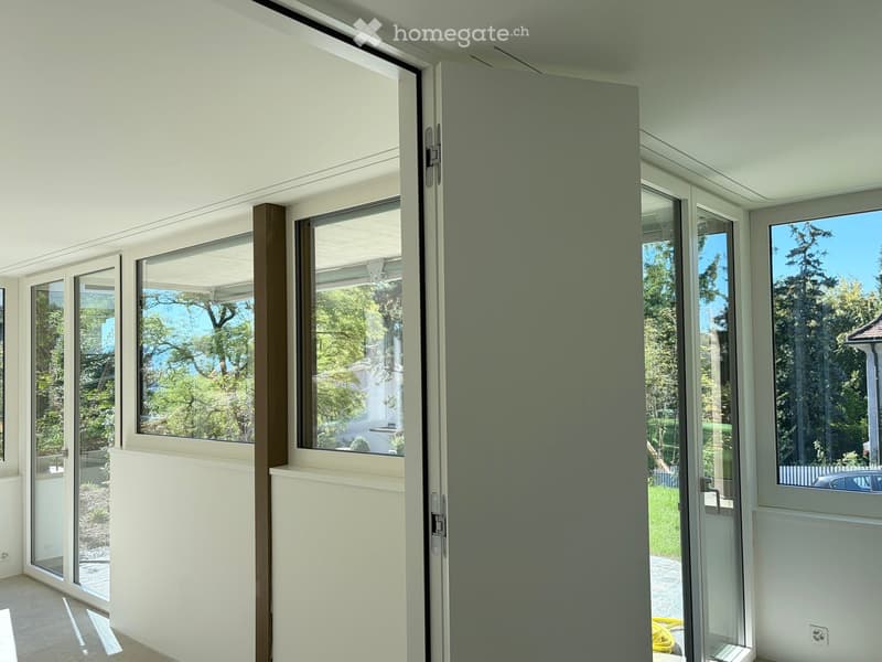 Empty room with large glass doors and windows, white walls, and a clean, modern design.