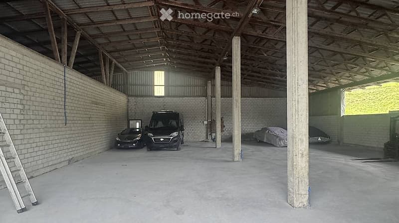 {"type": "Garage", "objects": [], "description": "Large, open garage with exposed wooden beams and concrete floor. Contains two parked vehicles, a ladder, and covered items in the background.", "visible_features": ["Garage"], "localized_descriptions": {"E