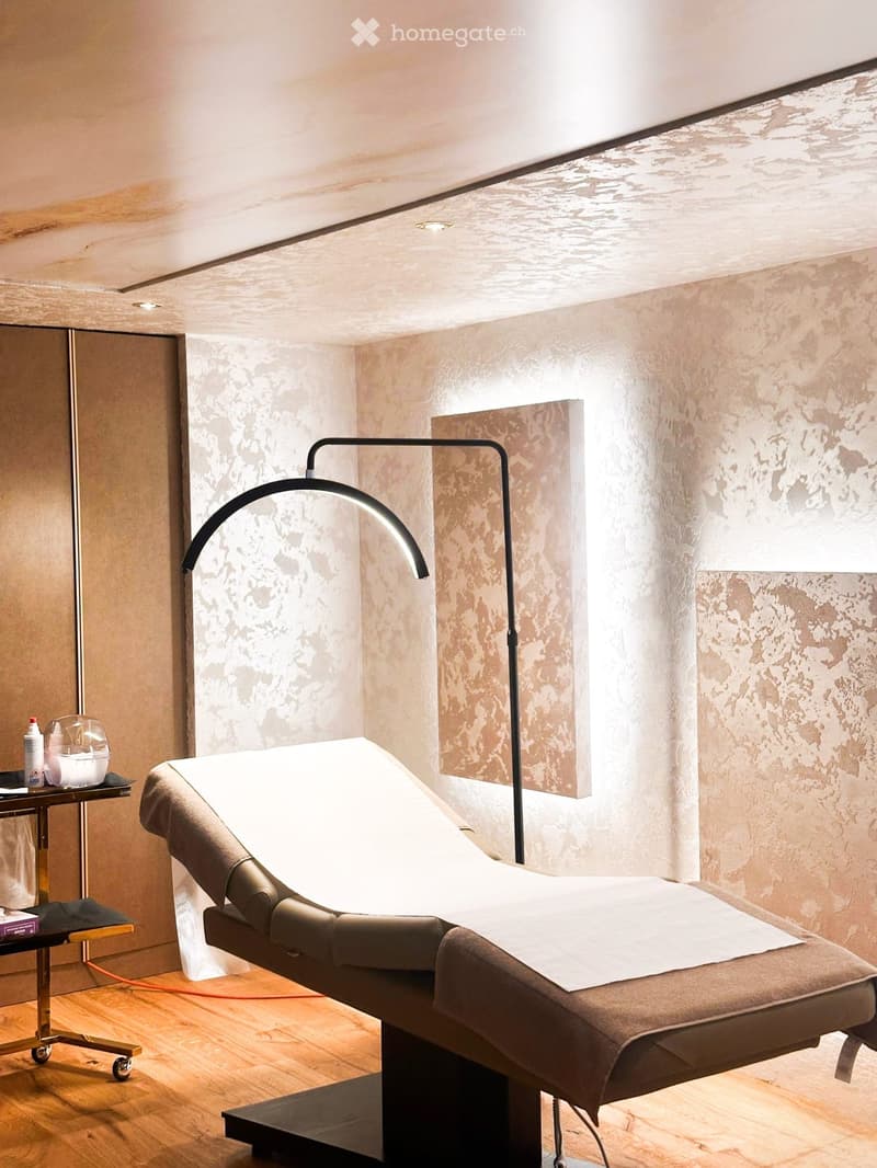 Modern bathroom with a massage table, sleek lamp, and small table with toiletries.